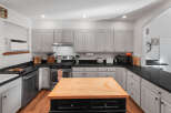 This spacious kitchen boasts ample cabinet space with light gray finishes and black granite countertops, perfect for meal preparation.