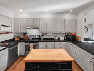 This spacious kitchen boasts ample cabinet space with light gray finishes and black granite countertops, perfect for meal preparation.