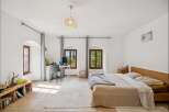 This bright and airy bedroom features a comfortable bed with a wooden headboard, perfect for restful nights.