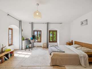 This bright and airy bedroom features a comfortable bed with a wooden headboard, perfect for restful nights.