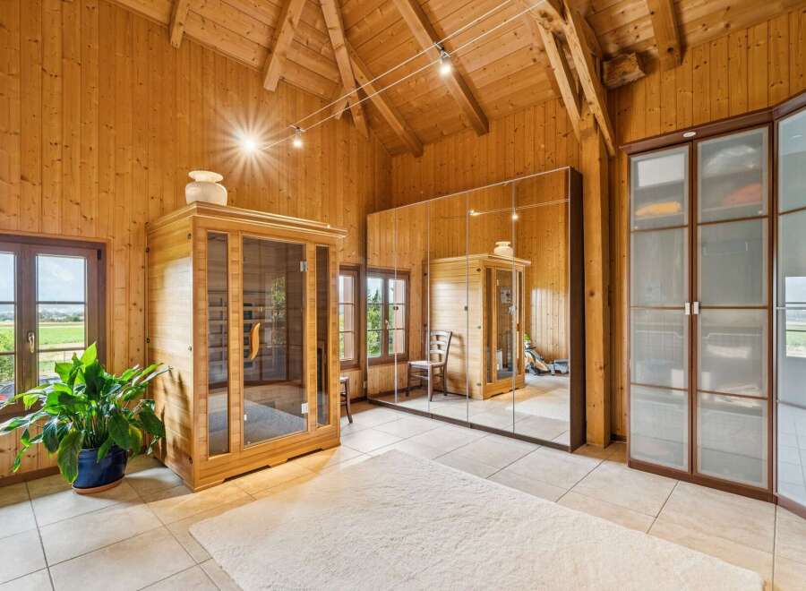 Experience ultimate relaxation in this stunning wooden room featuring a modern glass-enclosed sauna.