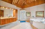 Experience luxury in this spacious bathroom featuring a large corner jacuzzi tub and a separate glass-enclosed shower.