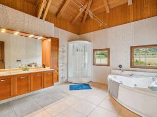 Experience luxury in this spacious bathroom featuring a large corner jacuzzi tub and a separate glass-enclosed shower.
