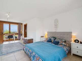 Experience comfort and style in this beautifully appointed bedroom, featuring a plush king-sized bed with a decorative headboard and vibrant floral bedding.