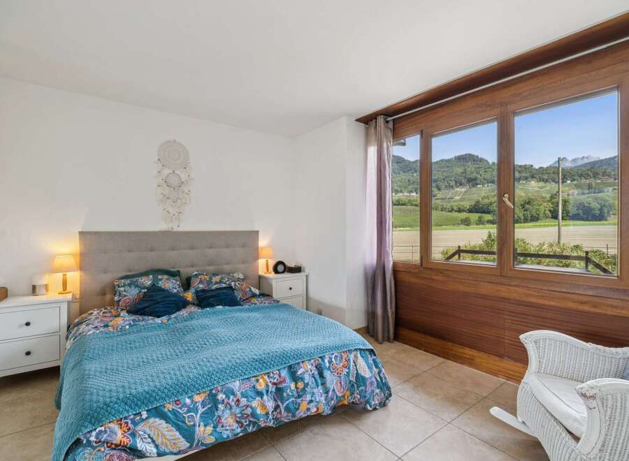 Experience breathtaking views from this charming bedroom, featuring a comfortable bed adorned with vibrant floral bedding and a cozy blue quilt.