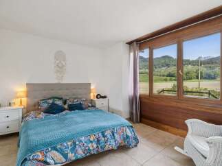 Experience breathtaking views from this charming bedroom, featuring a comfortable bed adorned with vibrant floral bedding and a cozy blue quilt.