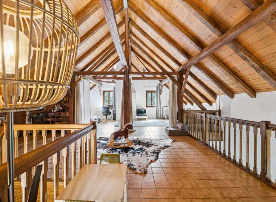 Discover this charming attic space featuring exposed wooden beams and a vaulted ceiling, creating a rustic and warm ambiance.