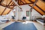 Discover this charming attic bedroom featuring exposed wooden beams and a sloped ceiling, creating a cozy and rustic ambiance.