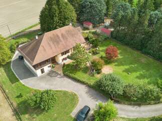 Discover this charming property featuring a spacious house with a classic tiled roof and warm yellow siding, complemented by a well-maintained lawn and mature trees.