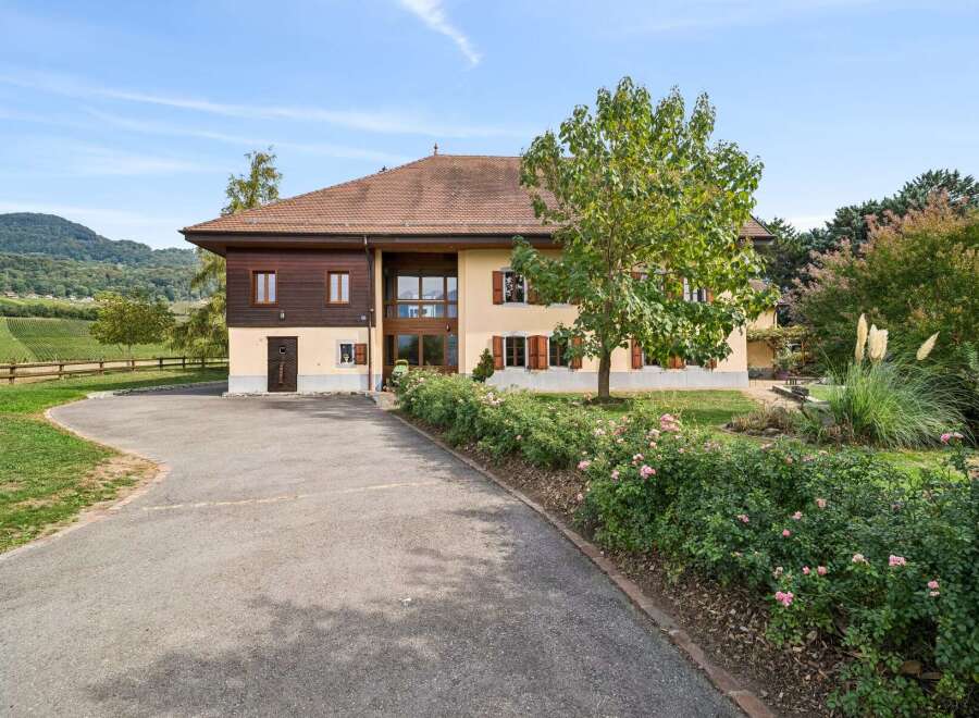Discover this charming property featuring a large house with a mix of wood and stucco facade, complemented by a beautiful garden with blooming roses and mature trees.