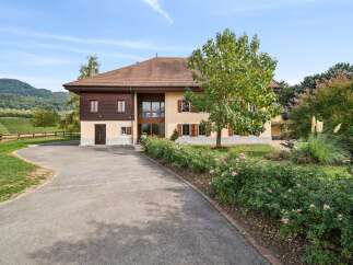 Discover this charming property featuring a large house with a mix of wood and stucco facade, complemented by a beautiful garden with blooming roses and mature trees.