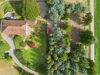 Discover this charming property featuring a spacious house with a red-tiled roof, surrounded by lush greenery and mature trees.