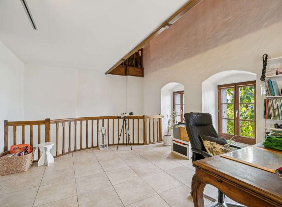 Discover a charming loft space featuring a cozy reading nook with a telescope and a dedicated workspace.