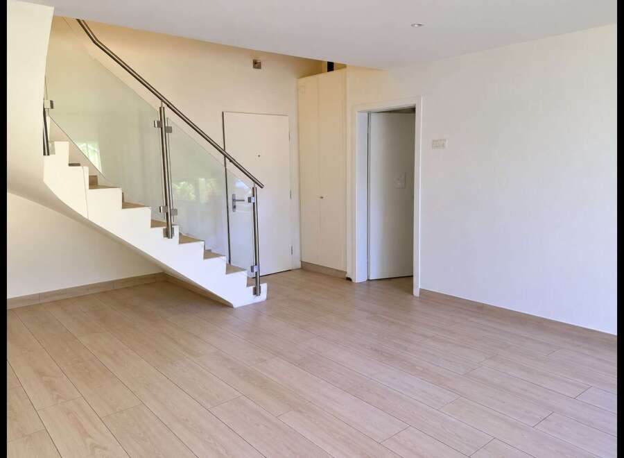 Step into this bright and airy home featuring a modern staircase with glass railings and sleek stainless steel accents.