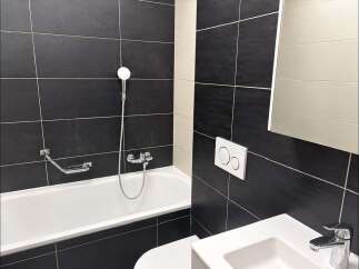 Experience modern comfort in this sleek bathroom, featuring a deep soaking tub with a chrome showerhead and a convenient soap dish.