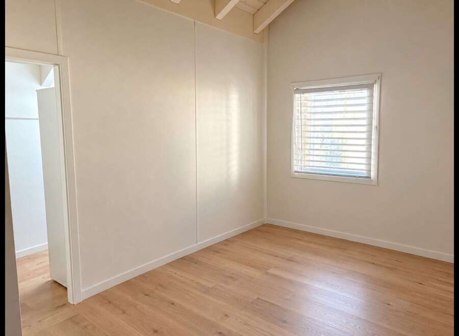 Discover this bright and airy room featuring a vaulted ceiling with exposed beams, creating a sense of spaciousness.