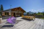 Enjoy breathtaking mountain views from the expansive wooden deck of this charming alpine chalet.