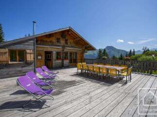 Enjoy breathtaking mountain views from the expansive wooden deck of this charming alpine chalet.