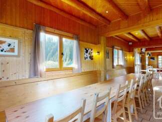 Experience rustic charm in this wood-paneled dining area, featuring a long, communal wooden table perfect for gathering.