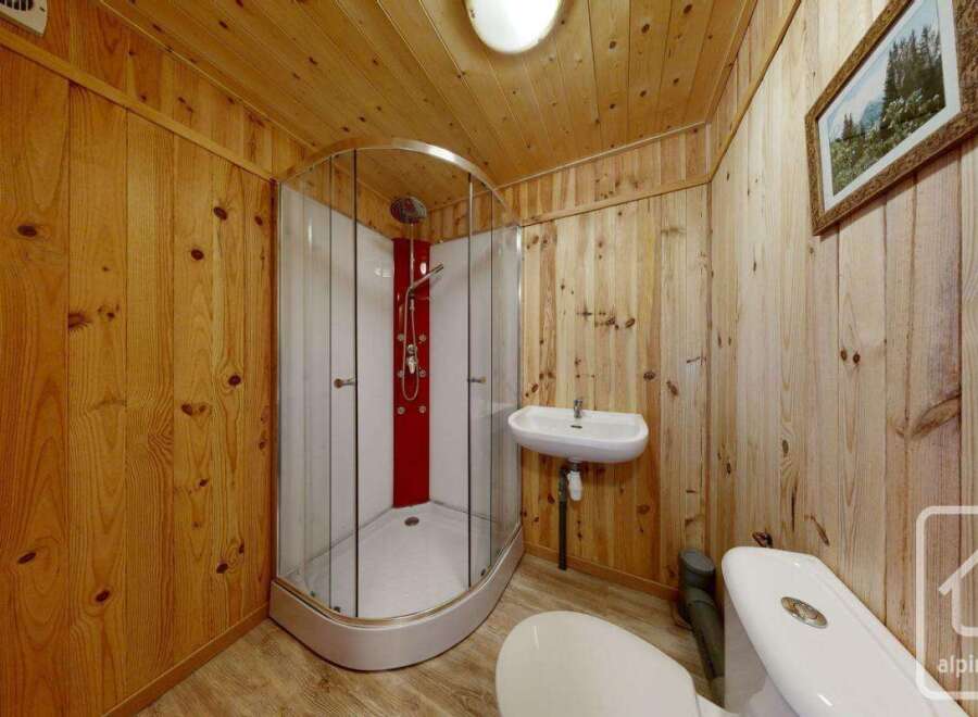 Experience rustic charm in this bathroom, featuring warm wooden paneling on the walls and ceiling.