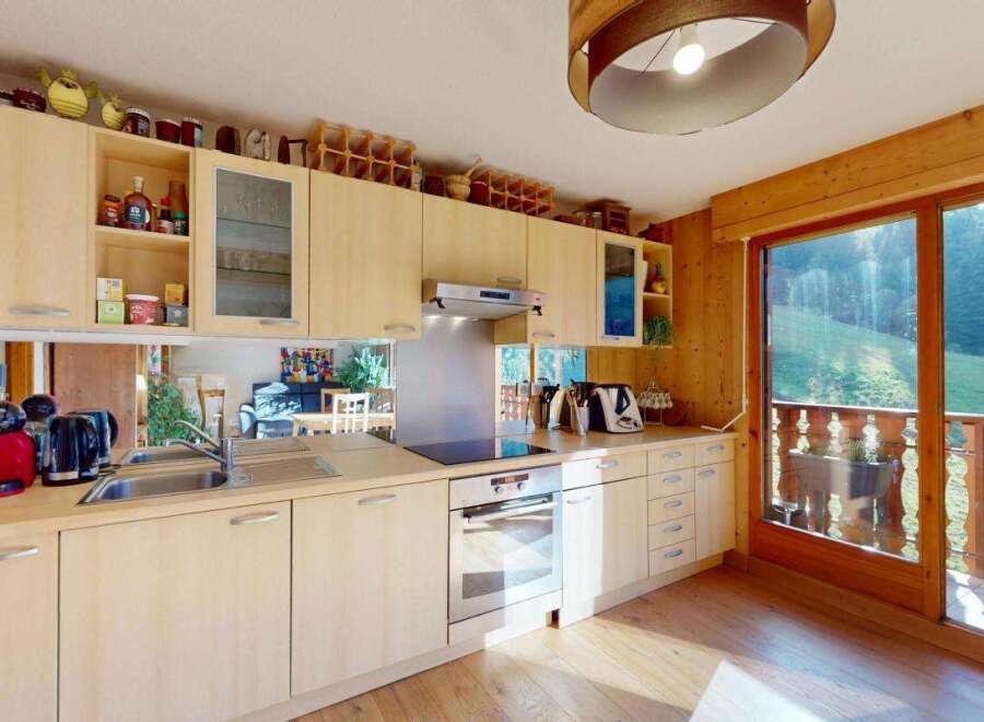 Experience the charm of this well-appointed kitchen, featuring light wood cabinetry and a sleek stainless steel backsplash.