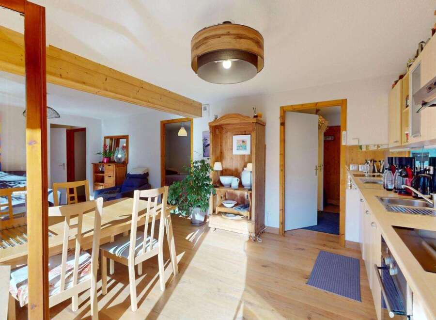 This charming open-plan living space features a bright and airy dining area with a wooden table and chairs, perfect for family meals.