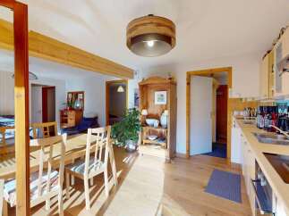 This charming open-plan living space features a bright and airy dining area with a wooden table and chairs, perfect for family meals.