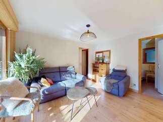 This inviting living room features a comfortable blue sectional sofa and a plush armchair, perfect for relaxing.