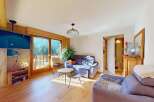 Experience breathtaking mountain views from this charming living room, featuring a cozy sofa and a large television mounted on a wooden accent wall.
