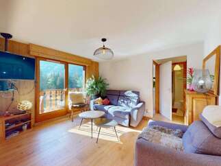 Experience breathtaking mountain views from this charming living room, featuring a cozy sofa and a large television mounted on a wooden accent wall.