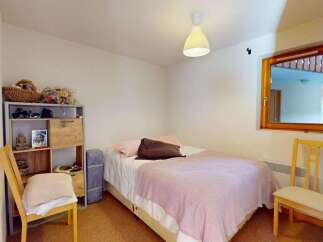 This cozy bedroom features a comfortable bed adorned with a pink throw blanket and plush pillows, perfect for relaxation.