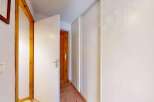 This hallway features a bright and airy feel, with a white door open to reveal a wooden interior door.
