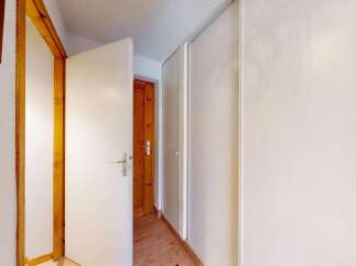 This hallway features a bright and airy feel, with a white door open to reveal a wooden interior door.