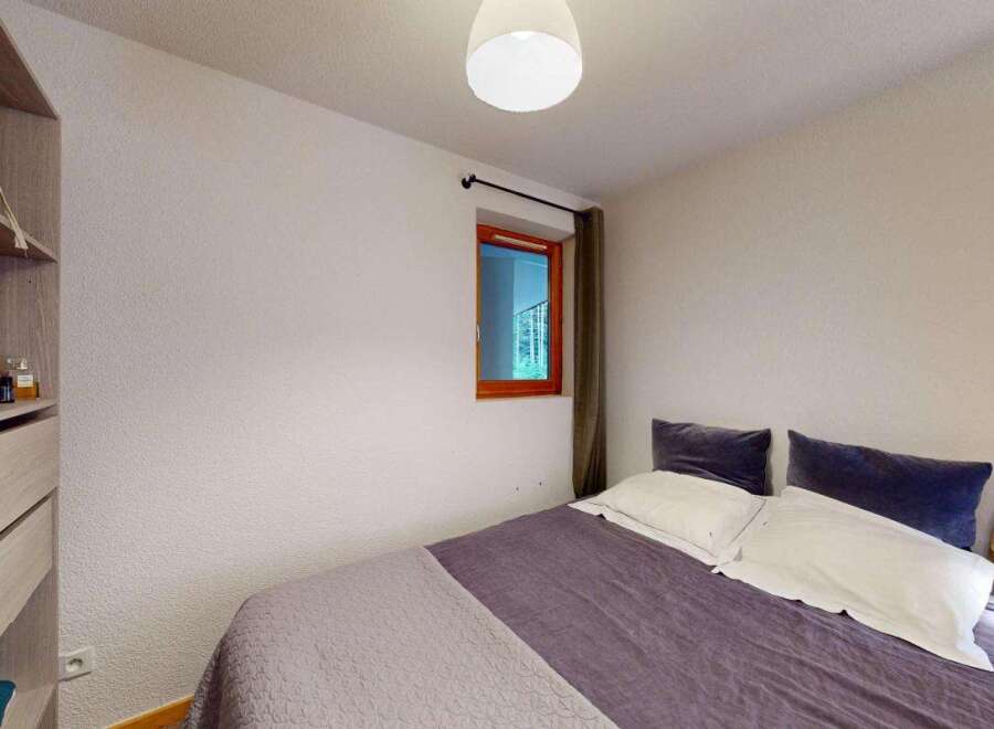 This cozy bedroom features a comfortable bed with plush pillows and a stylish purple duvet, perfect for relaxation.
