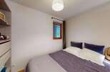 This cozy bedroom features a comfortable bed with plush pillows and a stylish purple duvet, perfect for relaxation.