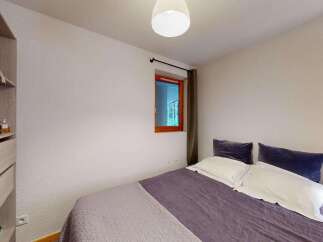 This cozy bedroom features a comfortable bed with plush pillows and a stylish purple duvet, perfect for relaxation.