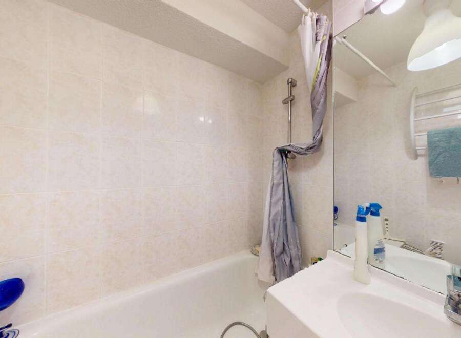 This bathroom features a clean and functional design with tiled walls and a bathtub.