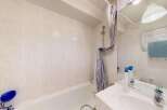 This bathroom features a clean and functional design with tiled walls and a bathtub.