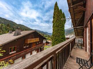 Enjoy breathtaking mountain views from the expansive wooden balcony of this charming alpine chalet.