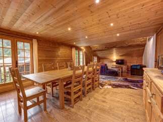 Experience rustic charm in this beautifully appointed wooden chalet, featuring a spacious dining area with a large wooden table and chairs, perfect for family gatherings.
