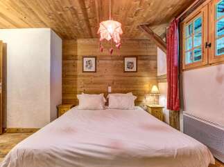Experience rustic charm in this cozy bedroom, featuring warm wooden walls and a comfortable queen-size bed adorned with crisp white linens.