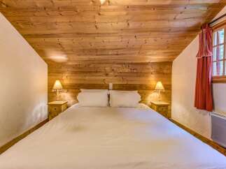 Experience cozy comfort in this charming bedroom, featuring a spacious bed adorned with crisp white linens.