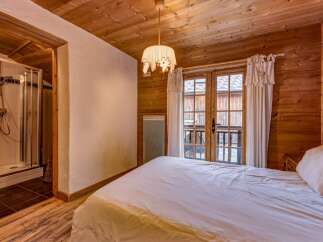 Experience cozy mountain living in this charming bedroom featuring rustic wooden walls and ceiling.