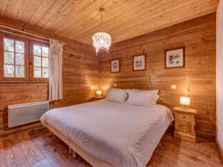 Experience rustic charm in this cozy wooden bedroom, featuring a comfortable queen-sized bed dressed in crisp white linens.