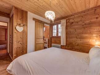 Experience cozy living in this charming wooden bedroom, featuring a comfortable bed dressed in crisp white linens.