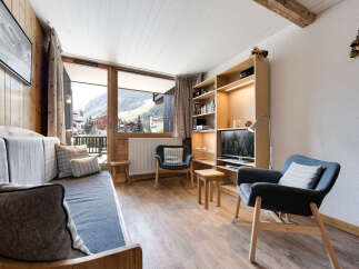 Experience cozy mountain living in this charming living room, featuring a comfortable sofa, two accent chairs, and a large bookshelf with integrated lighting.