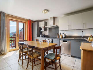 This charming kitchen boasts a rustic wooden dining table with four chairs, perfect for family meals.