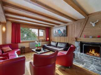 Experience cozy mountain living in this charming living room, featuring a roaring fireplace and plush red seating.