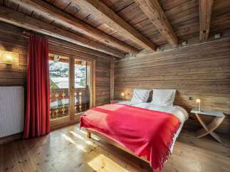 Experience rustic charm in this cozy bedroom, featuring warm wooden walls and exposed beams for a cabin-like feel.