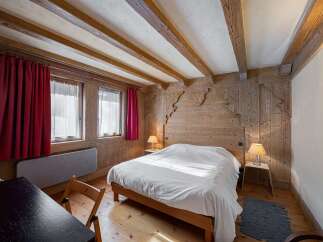 Experience rustic charm in this cozy bedroom, featuring exposed wooden beams and intricate wood paneling.